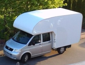 Große Absetzkabine ultraleicht auf VW Transporter Doppelkabine. 2 Meter langer Alkoven mit Längsbetten über dem Fahrerhaus, dahinter ca. 2,80 Meter lange Hauptkabine mit Doppelboden. Durchgang zum Fahrerhaus. Gerundete Form der Dachkontur nach Kundenwunsch.